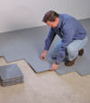 Contractors installing basement subfloor tiles and matting on a concrete basement floor in Mukilteo, Washington